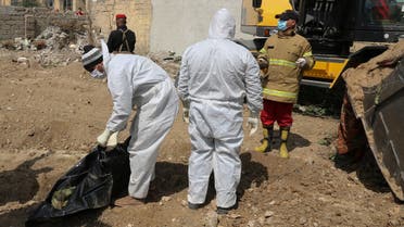 Iraqi forensic personnel examine human remains unearthed from a mass grave recently discovered in the northern Iraqi city of Mosul on March 20, 2022. (AFP)