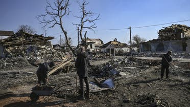 People clean up the debris from destroyed houses after bombardments in the village of Krasylivka, east of Kyiv, on March 20, 2022, as Russian forces try to encircle the Ukranian capital. (AFP)