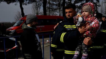 A firefighter carries a refugee child fleeing from Ukraine to Romania, following Russia's invasion of Ukraine, at the border crossing in Siret, Romania, March 20, 2022. REUTERS