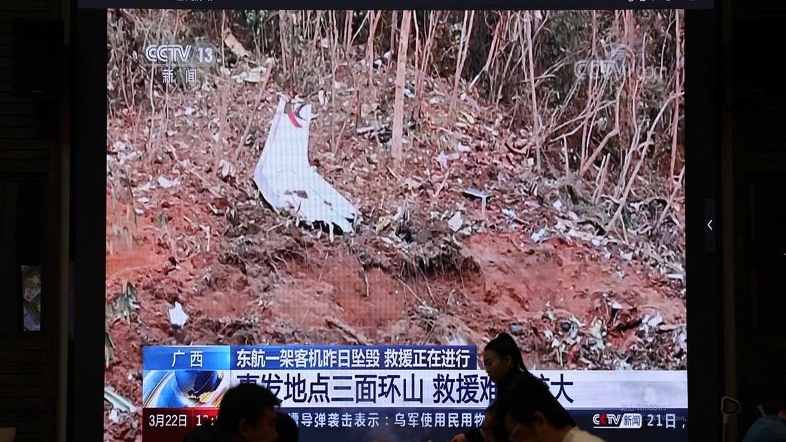 A screen shows news footage of plane debris at the site where a China Eastern Airlines Boeing 737-800 plane flying from Kunming to Guangzhou crashed in Wuzhou of Guangxi Zhuang Autonomous Region, while customers dine at a restaurant in Beijing, China March 22, 2022. (Reuters)