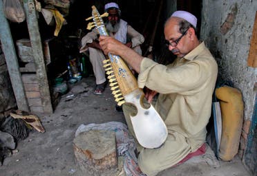 A man fixes strings on Rrubab, a traditional musical instrument originally from Afghanistan, at his shop in Peshawar April 16, 2011. (Reuters)