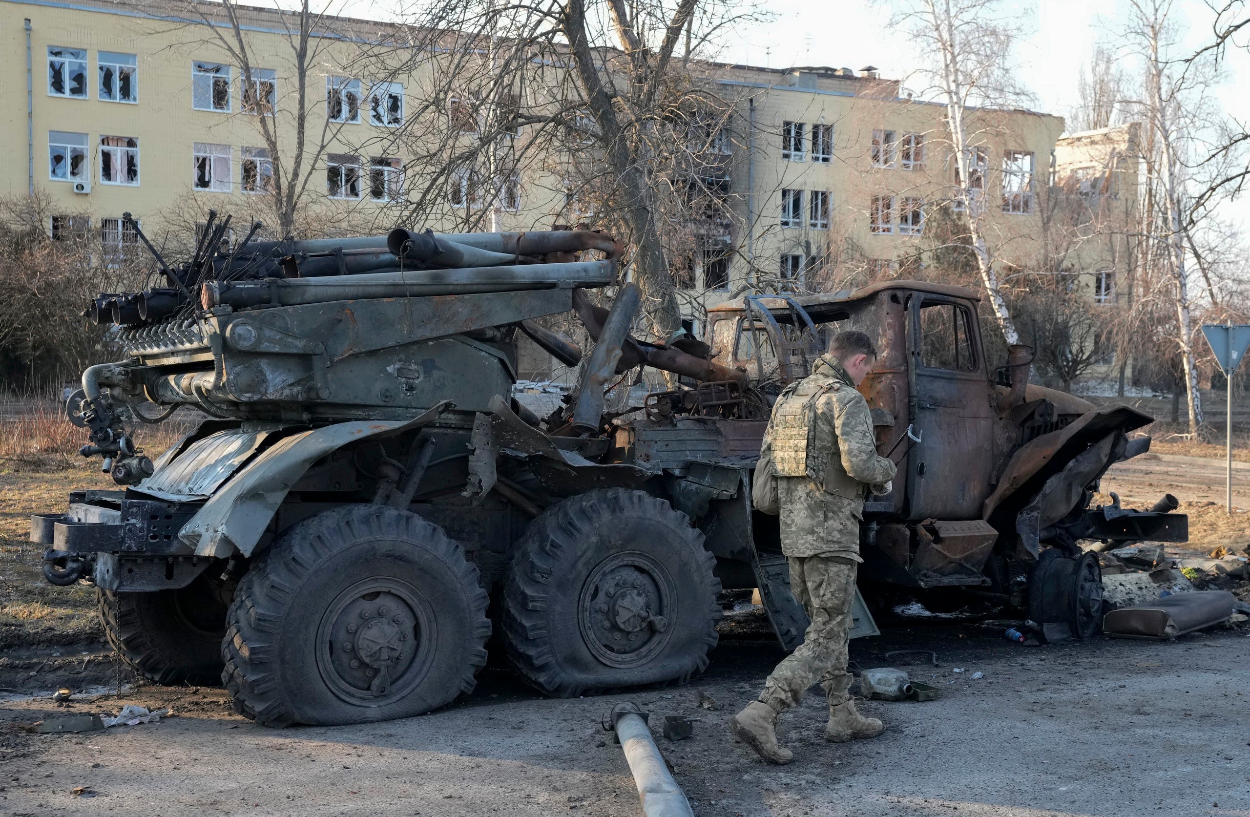 جندي أوكراني يمر جنب مدرعة روسية مدمرة