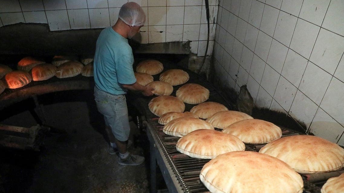 A worker stands near freshly baked bread at a bakery in Beirut, March 8, 2022. (Reuters)
