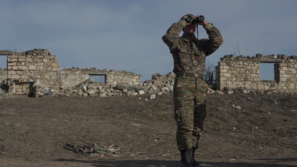 An ethnic Armenian soldier looks through binoculars as he stands at fighting positions in the region of Nagorno-Karabakh, January 11, 2021. (Reuters)