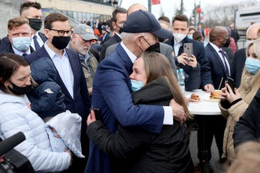 US President Joe Biden, flanked by Mayor of Warsaw Rafal Trzaskowski and Polish Prime Minister Mateusz Morawiecki, hugs a woman as he visits Ukrainian refugees at the PGE National Stadium, in Warsaw, Poland on March 26, 2022. (Reuters)