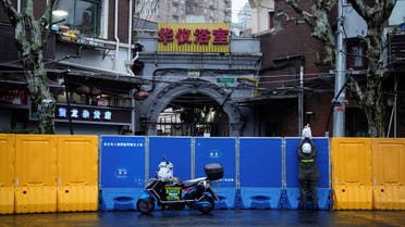 A delivery worker passes goods to a person over the barriers of an area under lockdown amid the coronavirus disease (COVID-19) pandemic, in Shanghai, China March 25, 2022. (Reuters)