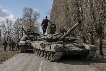 جندي أوكراني يقف فوق دبابة روسية في قرية لوكيانيفكا خارج كييف بأوكرانيا  - رويترز
