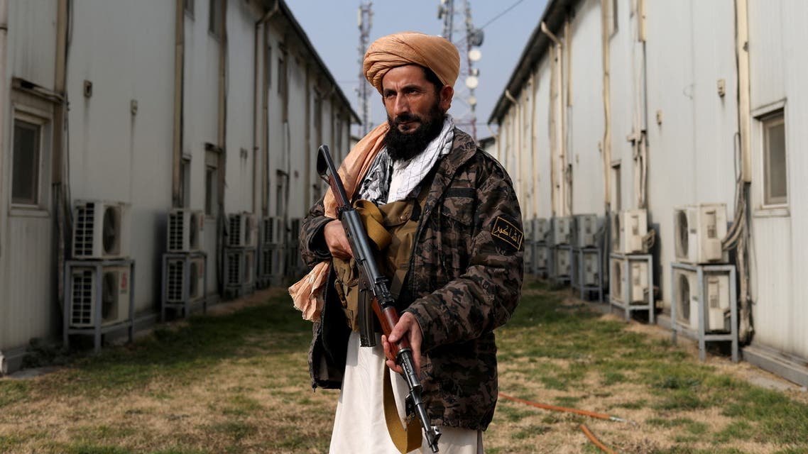A Taliban fighter stands guard as packages get distributed by a Turkish humanitarian aid group to Afghan people at a distribution centre in Kabul, Afghanistan, December 15, 2021. (Reuters)