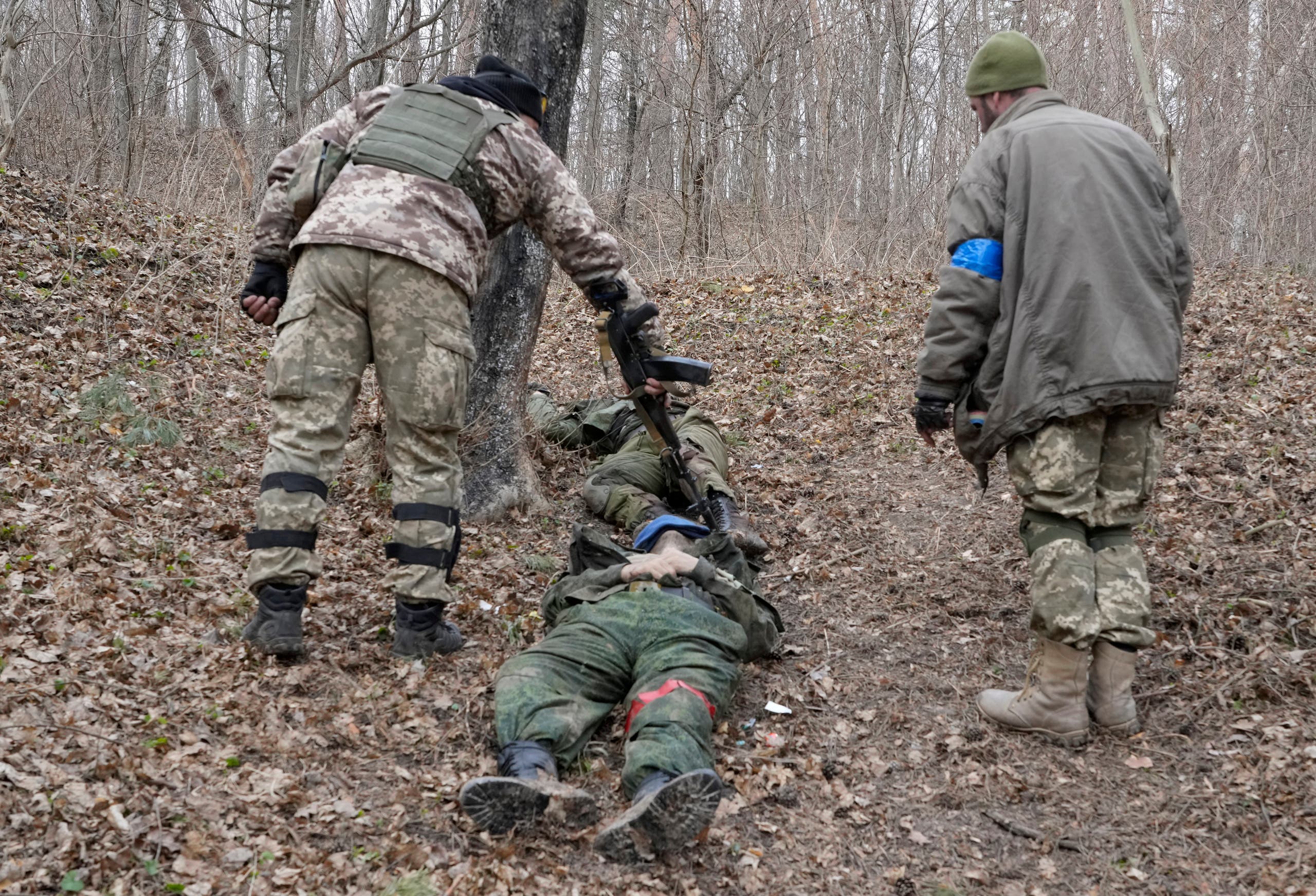 جندياتن اوكرانيان يتفقدان جثة جندي روسي في محيط كييف