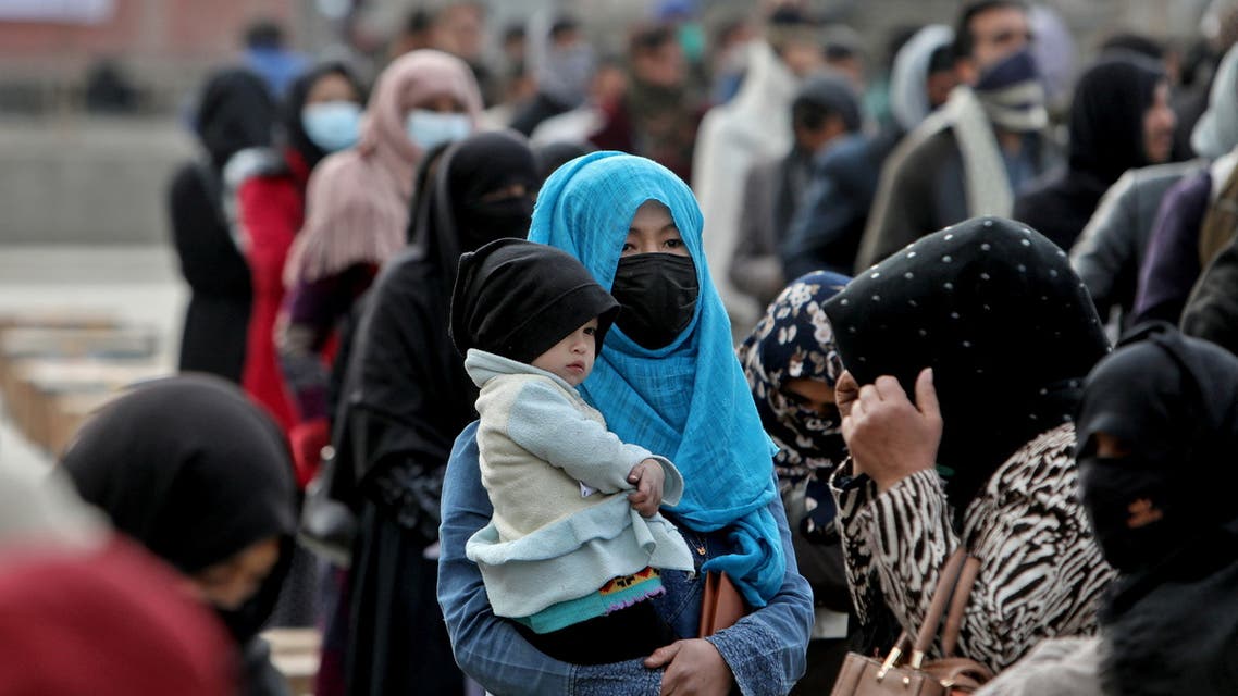 An Afghan woman holds her child as she and others wait to receive package being distributed by a Turkish humanitarian aid group at a distribution centre in Kabul, Afghanistan, December 15, 2021. (File photo: Reuters)