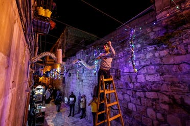 A man hangs decorations ahead of the holy month of Ramadan in Jerusalem's Old City, March 29, 2022. (Reuters)