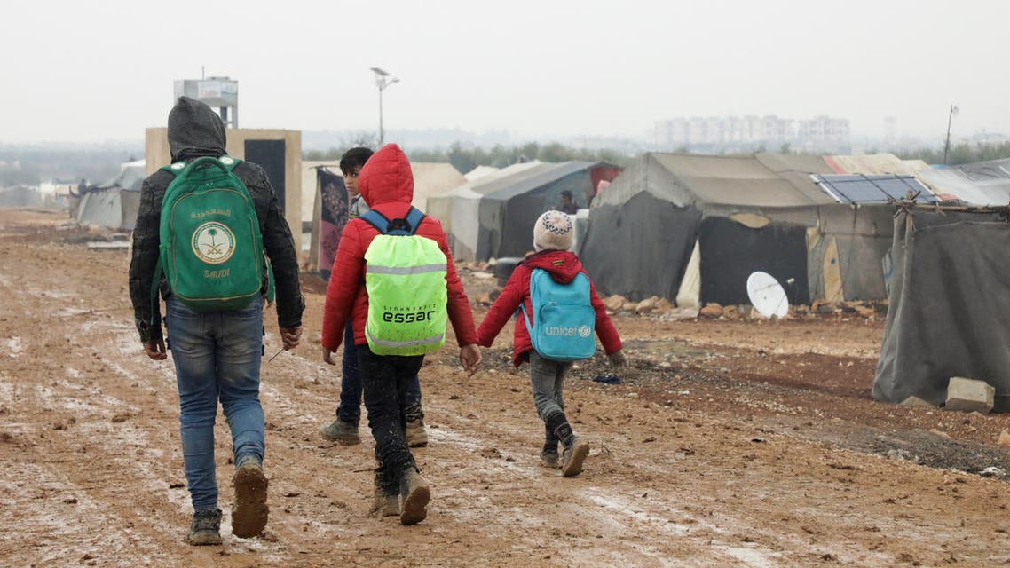 Internally displaced Syrians walk together near tents at a camp in Azaz, Syria March 1, 2022. (Reuters)