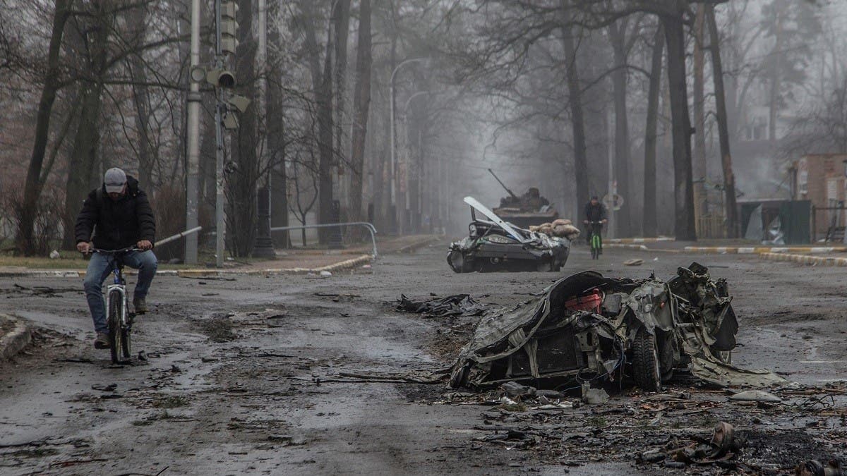 Local residents ride bicycles past flattened civilian cars, as Russia’s attack on Ukraine continues, on a street in the town of Bucha, in Kyiv region, Ukraine on April 1, 2022. (Reuters)