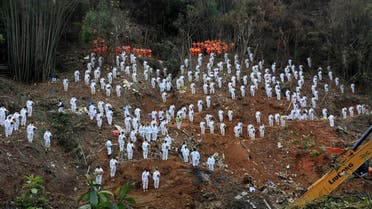 Rescue workers stand in a silent tribute at the site to mourn the victims of a China Eastern Airlines Boeing 737-800 plane, flight MU5735, that crashed in Wuzhou, Guangxi Zhuang Autonomous Region, China, March 27, 2022. (Reuters)