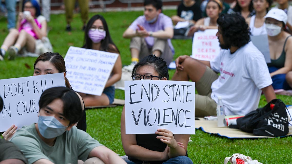 Attendees hold signs during a protest against the death penalty at Speakers' Corner in Singapore on April 3, 2022. (AFP)