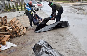 Communal workers carry the body of a man into a body bag of the town of Bucha, not far from the Ukrainian capital of Kyiv on April 3, 2022. (AFP)