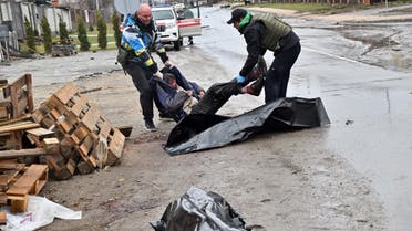 Communal workers carry the body of a man into a body bag of the town of Bucha, not far from the Ukrainian capital of Kyiv on April 3, 2022. (AFP)