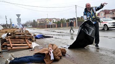  A body of a civilian man with hands tied behind his back lies in the street as a communal worker prepares a plastic body bag to carry him to a waiting car in town of Bucha, not far from the Ukrainian capital of Kyiv on April 3, 2022. (AFP)