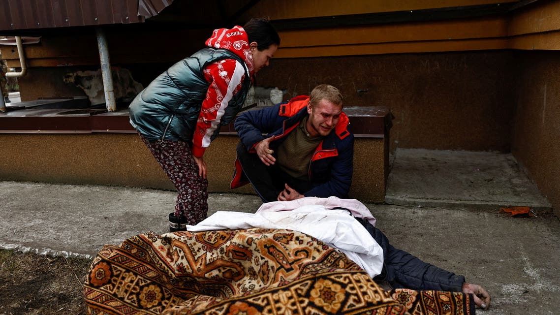 Serhii Lahovskyi, 26, and his wife Alesia mourn by the body of their friend Ihor Lytvynenko, who according to residents was killed by Russian Soldiers, after they found him beside a building's basement, amid Russia's invasion of Ukraine, in Bucha, Ukraine April 5, 2022. (Reuters)