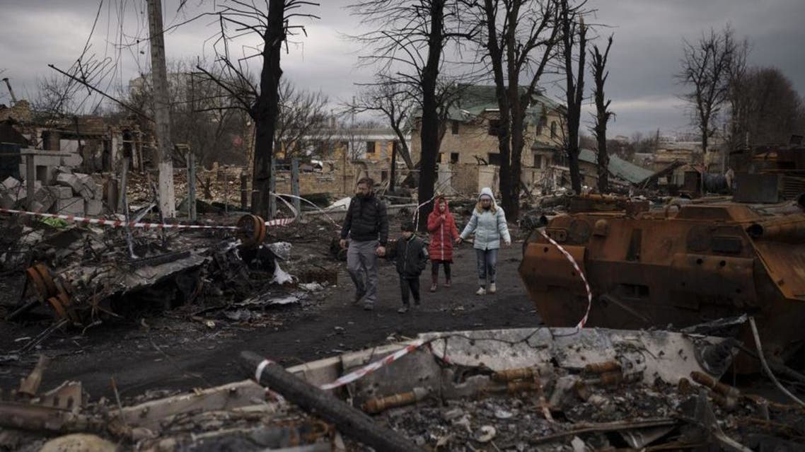 A family walks amid destroyed Russian tanks in Bucha, on the outskirts of Kyiv, Ukraine, Wednesday, April 6, 2022. (AP)