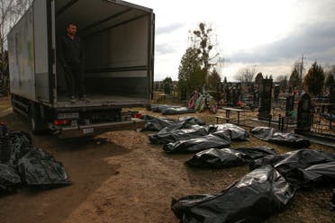 A funeral service employee looks at bodies of civilians, collected from streets to local cemetery, as Russia's attack on Ukraine continues, in the town of Bucha, outside Kyiv, Ukraine April 6, 2022. (Reuters)