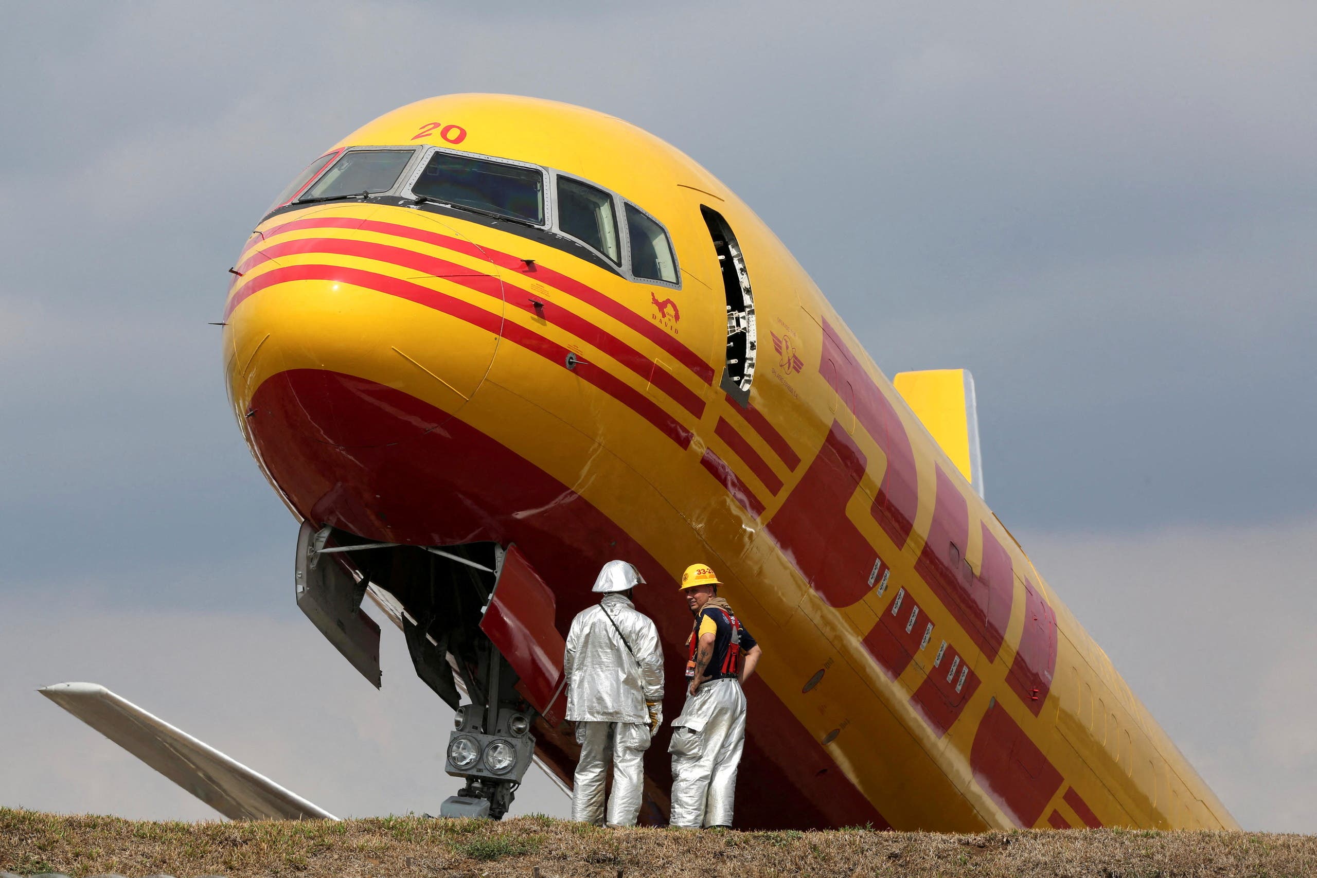 Firefighters stand at the scene where a Boeing 757-200 cargo aircraft operated by DHL made an emergency landing before skidding off the runway and splitting, aviation authorities said, at the Juan Santamaria International Airport in Alajuela, Costa Rica April 7, 2022. (Reuters )