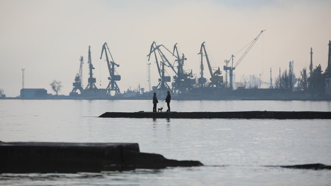 A couple walks a dog on a pier at a coast of the Sea of Azov in Ukraine's industrial port city of Mariupol on February 23, 2022. Mariupol lies on the edge of the front line separating government-controlled territory from that overseen by Russian-backed separatists in the rebel stronghold Donetsk. (Photo by Aleksey Filippov / AFP)
