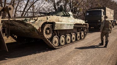 A Ukrainian serviceman walks near a Russian army tank in the northeastern city of Trostyanets', on March 29, 2022. (AFP)