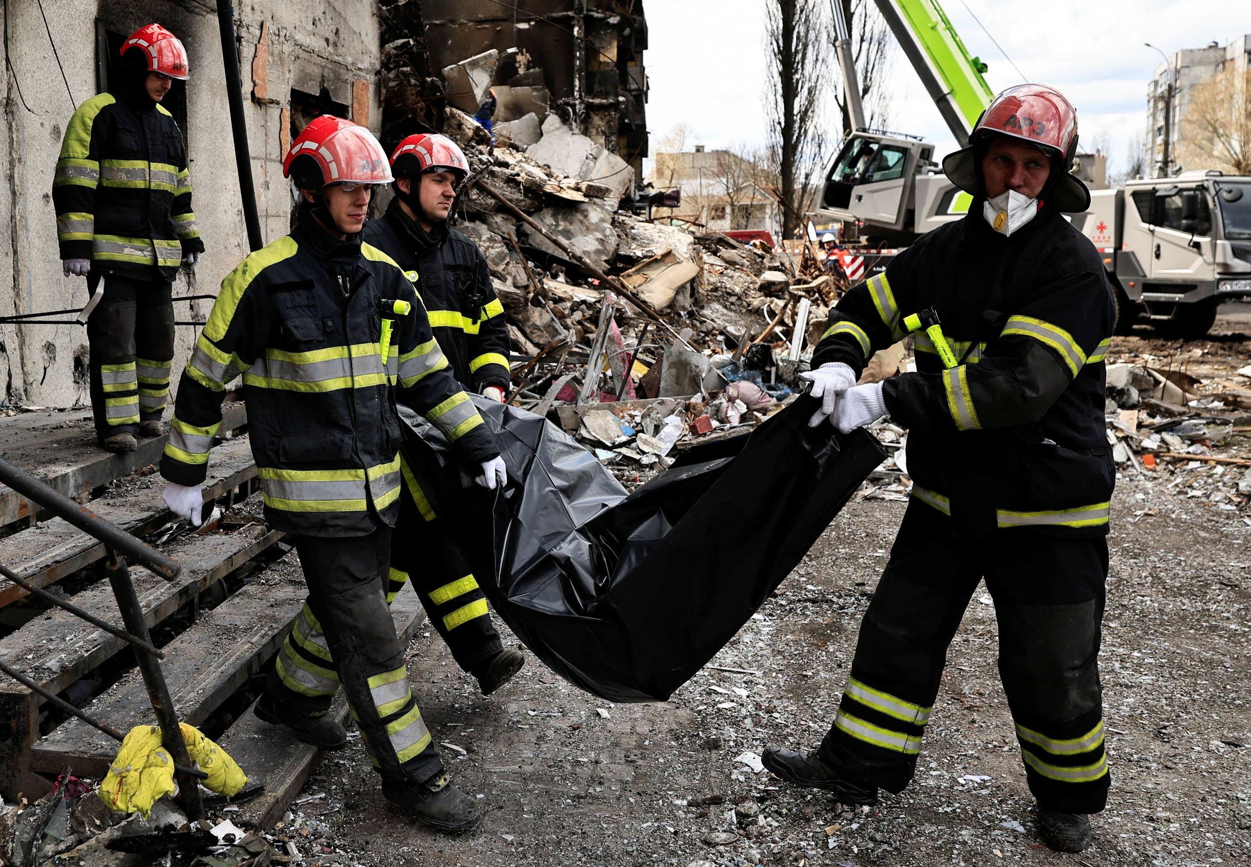 عمال الإنقاذ يحملون جثة امرأة ، تم العثور عليها داخل مبنى دمره القصف الروسي، في بورودينكا قرب كييف 