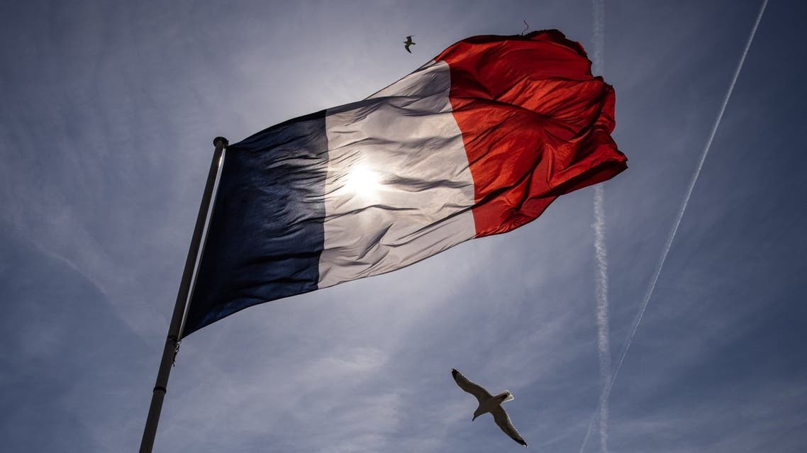 A picture taken on April 10, 2022 shows the sun shining through a French national flag in the Mont Saint-Michel. (Reuters)