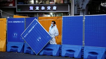 A worker in a protective suit keeps watch next to barricades set around a sealed-off area, during a lockdown to curb the spread of the coronavirus disease (COVID-19) in Shanghai, China April 11, 2022. (Reuters)