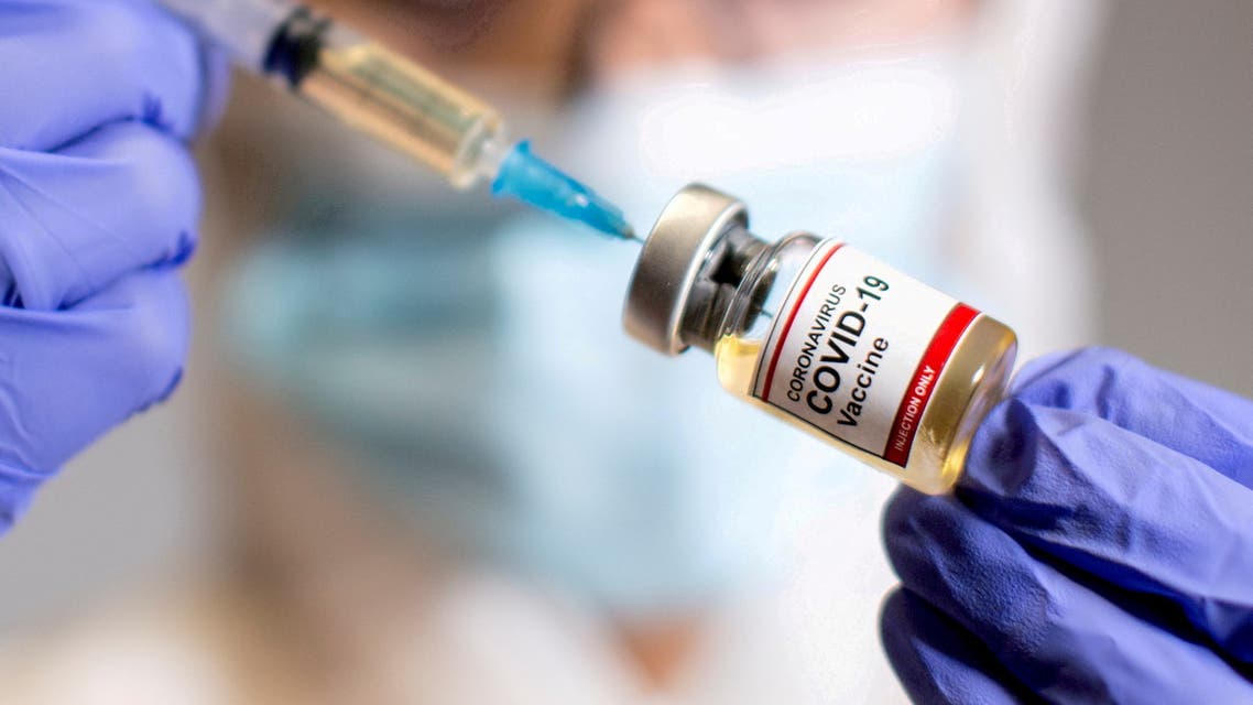 A woman holds a small bottle labelled with a Coronavirus COVID-19 Vaccine sticker and a medical syringe in this illustration taken October 30, 2020. (File Photo: Reuters)