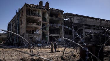 People stand beside damaged buildings at the Vizar company military-industrial complex, after the site was hit by overnight Russian strikes, in the town of Vyshneve, southwestern suburbs of Kyiv, on April 15, 2022. (AFP)