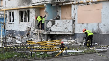 Communal services workers board up holes in walls and broken windows at a residential building damaged by shelling, in Kharkiv, on April 14, 2022. (AFP)