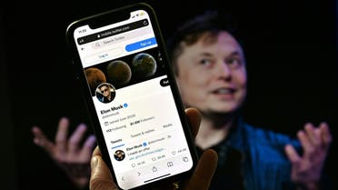 In this photo illustration, a phone screen displays the Twitter account of Elon Musk with a photo of him shown in the background, on April 14, 2022, in Washington, DC. (AFP)