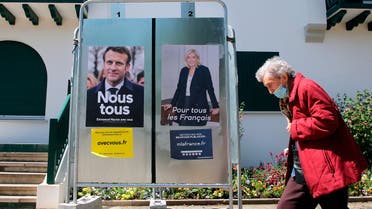 A woman walks past presidential campaign posters of French President and centrist candidate for reelection Emmanuel Macron and French far-right presidential candidate Marine Le Pen in Anglet, southwestern France, Saturday, April 16, 2022. France will vote on Sunday April 24 in the second round of the presidential election. (AP Photo/Bob Edme)