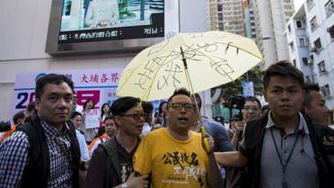 Pro-democracy activist Tam Tak-chi holds a yellow umbrella, the symbol of the Occupy Central movement, as he is escorted away by police after confronting government supporters as Chief Secretary Carrie Lam is pictured on a giant television screen during a promotional event she led on electoral reform, in Hong Kong, China April 25, 2015. The Hong Kong government has published a long-awaited electoral blueprint for selecting the city's next leader, a plan enshrining China's desire for a tightly controlled poll that has angered activists and stoked talk of fresh protests. (Reuters)