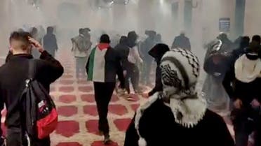 A worshiper wears a Palestinian flag, as smoke is seen inside the al-Aqsa mosque known to Muslims as the Noble Sanctuary and to Jews as the Temple Mount, during clashes with Israeli security forces, in Jerusalem's Old City, April 15, 2022 in this still image obtained from a social media video. Mujahed Hamayel/via REUTERS THIS IMAGE HAS BEEN SUPPLIED BY A THIRD PARTY. MANDATORY CREDIT. NO RESALES. NO ARCHIVES.