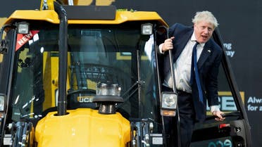 British Prime Minister Boris Johnson climbs over a JCB at the new JCB Factory during his two day trip to India, in Vadodara, Gujarat, India, on April 21, 2022. (Reuters)