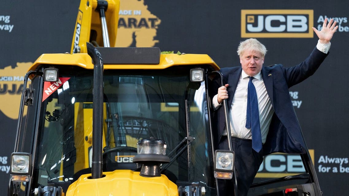British Prime Minister Boris Johnson climbs over a JCB at the new JCB Factory during his two day trip to India, in Vadodara, Gujarat, India April 21, 2022. (Reuters)