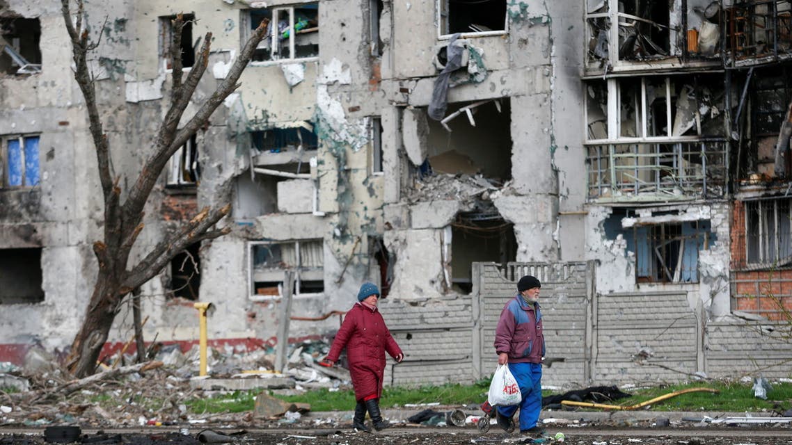 People walk near a residential building destroyed during Ukraine-Russia conflict in the southern port city of Mariupol, Ukraine April 22, 2022. (Reuters)