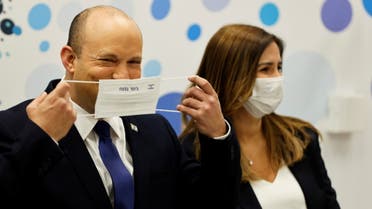 Israeli Prime Minister Naftali Bennett smiles as he adjusts his protective mask during his visit to a Maccabi healthcare maintenance organisation (HMO) outlet which offers vaccinations against the coronavirus disease (COVID-19) in Holon, near Tel Aviv, Israel June 29, 2021. REUTERS/Amir Cohen