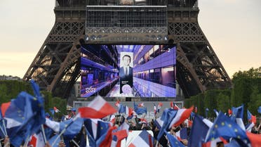 Supporters react after the victory of French President and La Republique en Marche (LREM) party candidate for re-election Emmanuel Macron in France's presidential election, at the Champ de Mars, in Paris, on April 24, 2022. (AFP)