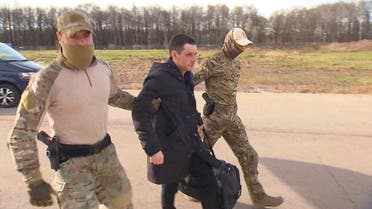 Former US Marine Trevor Reed, who was detained in 2019 and accused of assaulting police officers, is escorted to a plane by Russian service members as part of a prisoner swap between the US and Russia, in Moscow, Russia, in this still image taken from video released on April 27, 2022. (Reuters)