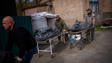 US Volunteers Wade Helton, right, and Darrell Loveless, center, work moving dead bodies from refrigerated trucks to the morgue in Bucha, on the outskirts of Kyiv, Monday, April 25, 2022. (AP Photo/Emilio Morenatti)
