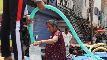 A woman fills a plastic container with drinking water from a municipal tanker, on a hot summer day in New Delhi, India, on May 1, 2022. (Reuters)