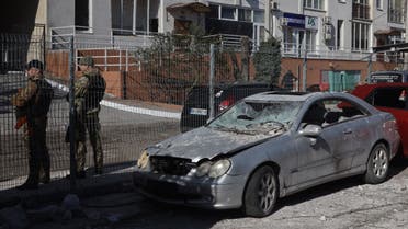 جنود أوكرانيون يقفون بجانب سيارة مدمرة أمام مبنى مدمر في أوديسا ، جنوب أوكرانيا في 24 أبريل 2022 ، والذي ورد أنه أصيب بضربة صاروخية. (أ ف ب)
