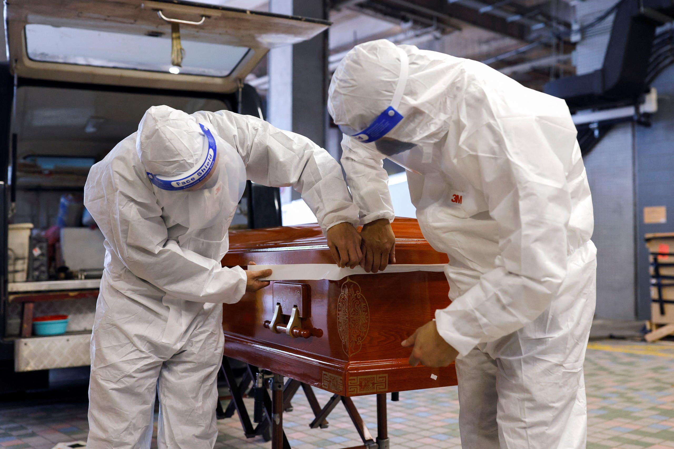 Funeral workers wear personal protective equipment (PPE) as they seal up a coffin of coronavirus disease (COVID-19) victim before cremation, in Hong Kong, China, on April 1, 2022. (Reuters)