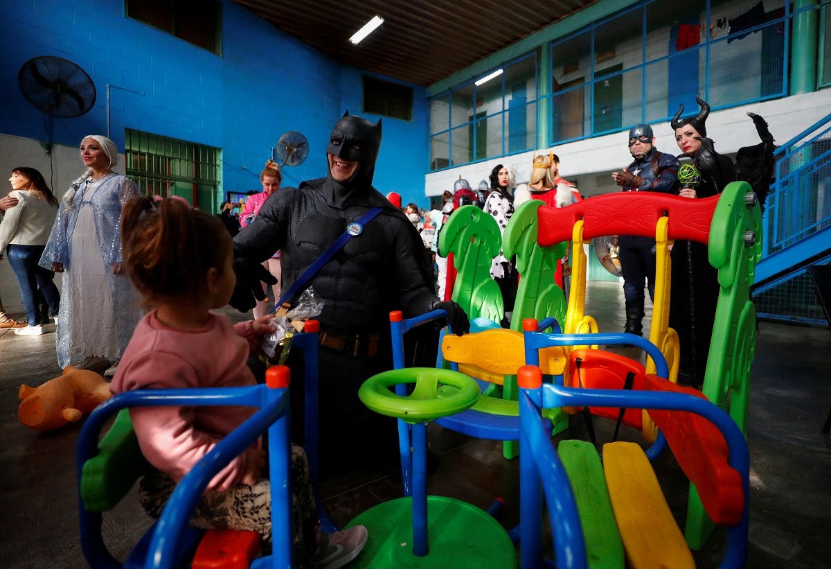 Argentine volunteer and organizer of the so-called Hero Club (Club de Heroes), Damian Gomez, who impersonates comic book superhero Batman, plays with the daughter of an inmate during a visit at the 33rd prison in Los Hornos as part of a wider program for vulnerable minors, on the outskirts of Buenos Aires, Argentina April 30, 2022. (Reuters)