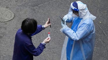 FILE PHOTO: A worker in a protective suit checks QR code on the phone of a resident for nucleic acid testing during lockdown, amid the coronavirus disease (COVID-19) pandemic, in Shanghai, China, April 26, 2022. REUTERS/Aly Song/File Photo